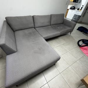 ספה אפורה עם ציוד ניקוי על הרצפה