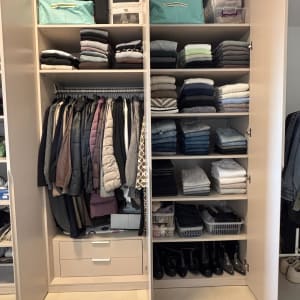 ארון בגדים מסודר עם בגדים מקופלים ומעילים תלויים