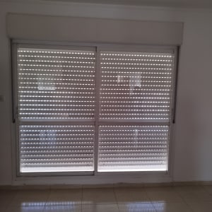 תריסים סגורים עם חריצים לאור על חלון זכוכית