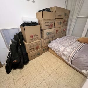 קופסאות קרטון לאריזה מונחות בחדר ליד מיטה