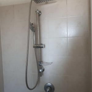 ראש מקלחת ומערכת מים על קיר אריחים