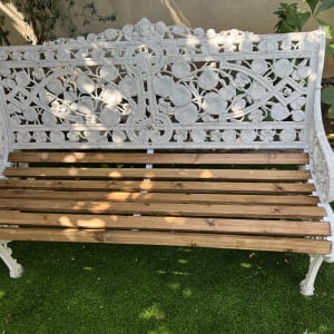 ספסל עץ ומתכת בגינה על דשא סינתטי