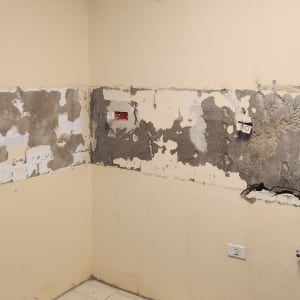 קיר עם טיח מתקלף ושקעים חשמליים חשופים