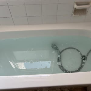 אמבטיה מלאה במים עם ראש מקלחת וכיסוי קרמיקה