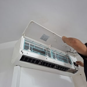 אדם מתקין מזגן על קיר לבן