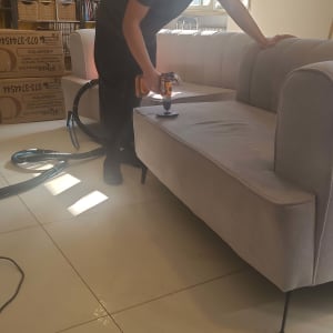 אדם מנקה ספה עם מכשיר חשמלי בחדר מואר