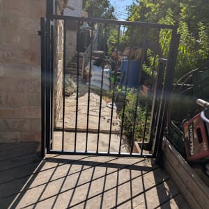 שער מתכת בכניסה לחצר עם צללים על הרצפה