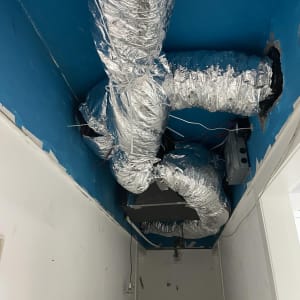 צינורות מיזוג אוויר מכוסים בנייר כסף בתקרה כחולה