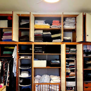 ארון בגדים מסודר עם מדפים פתוחים ותיק על המיטה