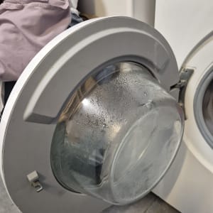 דלת מכונת כביסה פתוחה עם בגדים רטובים