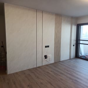 חדר עם רצפת פרקט וקיר מעוצב ליד חלון גדול