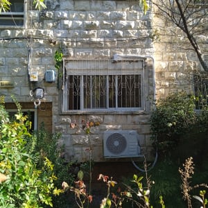 יחידת מיזוג אוויר מותקנת על קיר חיצוני של בניין אבן.