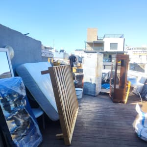 רהיטים וציוד ארוזים על מרפסת לקראת מעבר דירה.