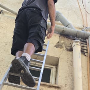 אדם על סולם ליד צינורות חיצוניים