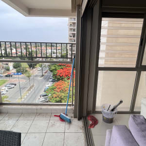 מטאטא כחול ואדום, דלי עם מברשות וסמרטוט אדום על מרפסת