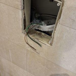 תמונה של קיר עם חור וצינורות חשופים