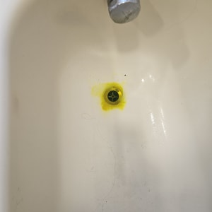 כיור עם סימני דליפה בצבע צהוב סביב הניקוז