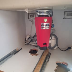 מתקן אדום מתחת לכיור עם צינורות חיבור