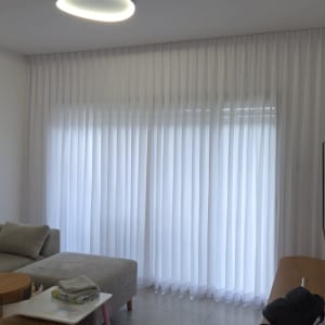 וילון לבן בסלון עם ספה ושולחן קטן