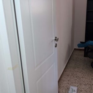 דלת לבנה עם ידית כסופה פתוחה חלקית