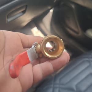 ברז פליז עם ידית אדומה מוחזק ביד