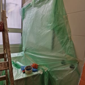 חדר עם כיסוי פלסטיק ירוק וסולם ליד חלון