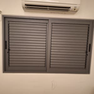 חלון אלומיניום עם תריסים סגורים ומזגן מעליו