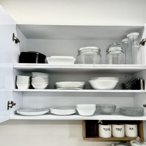 ארון מטבח פתוח עם צלחות, קערות וצנצנות זכוכית