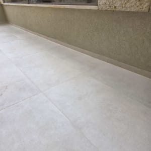 מרפסת עם ריצוף חדש ומעקה זכוכית