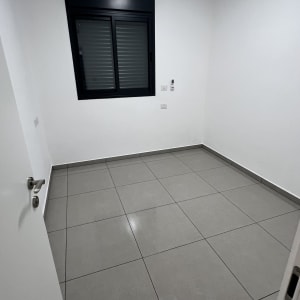 חדר ריק עם רצפת אריחים נקייה וחלון סגור