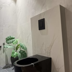 אסלה שחורה תלויה על קיר עם אריחי שיש