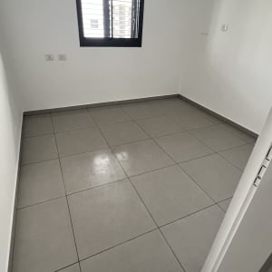 חדר ריק עם רצפת אריחים נקייה וקירות לבנים