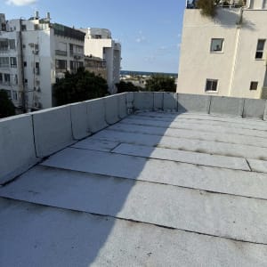 גג אטום עם נוף לבניינים ולים ברקע