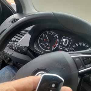 מפתח רכב חכם ביד מול הגה ומד מהירות