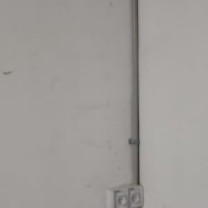 שקע חשמל כפול על קיר לבן עם צינור חשמל