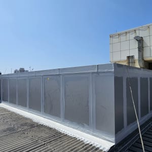 קיר אטום על גג עם צינורות ומבנה תעשייתי ברקע