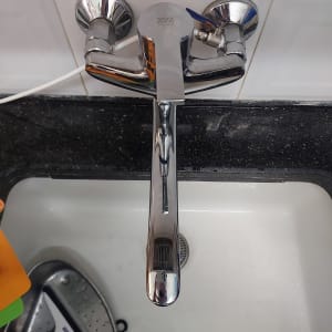 ברז כרום מעל כיור עם אריחי קרמיקה לבנים