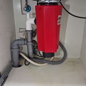 מתקן אדום מתחת לכיור עם צינורות חיבור