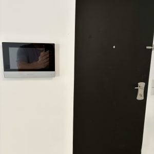 מסך אינטרקום ליד דלת כניסה שחורה