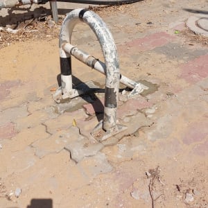 מחסום מתכת ישן על מדרכה מרוצפת