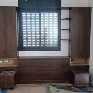 ארון עץ כהה עם מדפים ומגירות ליד חלון