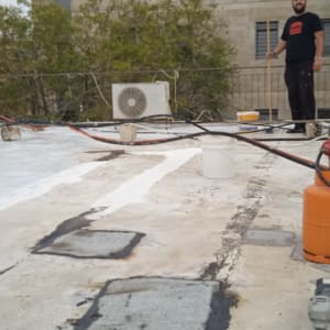 אדם על גג עם ציוד לאיטום וזפת