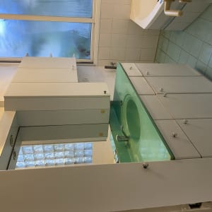 כיור ירוק עם ארונות לבנים בחדר אמבטיה