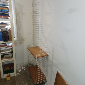 חדר עם מדף מתכת, ספרים וכלים על הרצפה