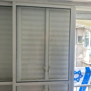 חלון זכוכית עם תריסים סגורים ומסגרת לבנה