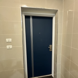 דלת כחולה עם ידית מתכת במסגרת לבנה