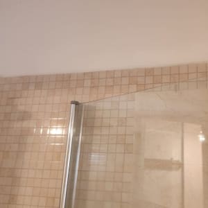 דלת זכוכית למקלחת עם אריחי קרמיקה על הקיר