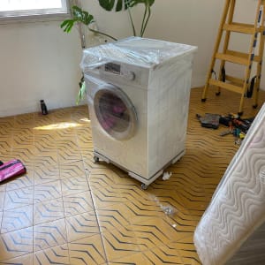 מכונת כביסה עטופה בניילון ליד סולם וכלים