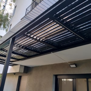 פרגולה מתכתית עם קורות עץ בגינה