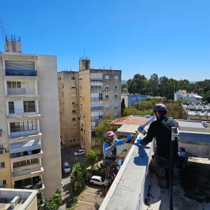 שני עובדים על גג עם ציוד טיפוס וחבלים